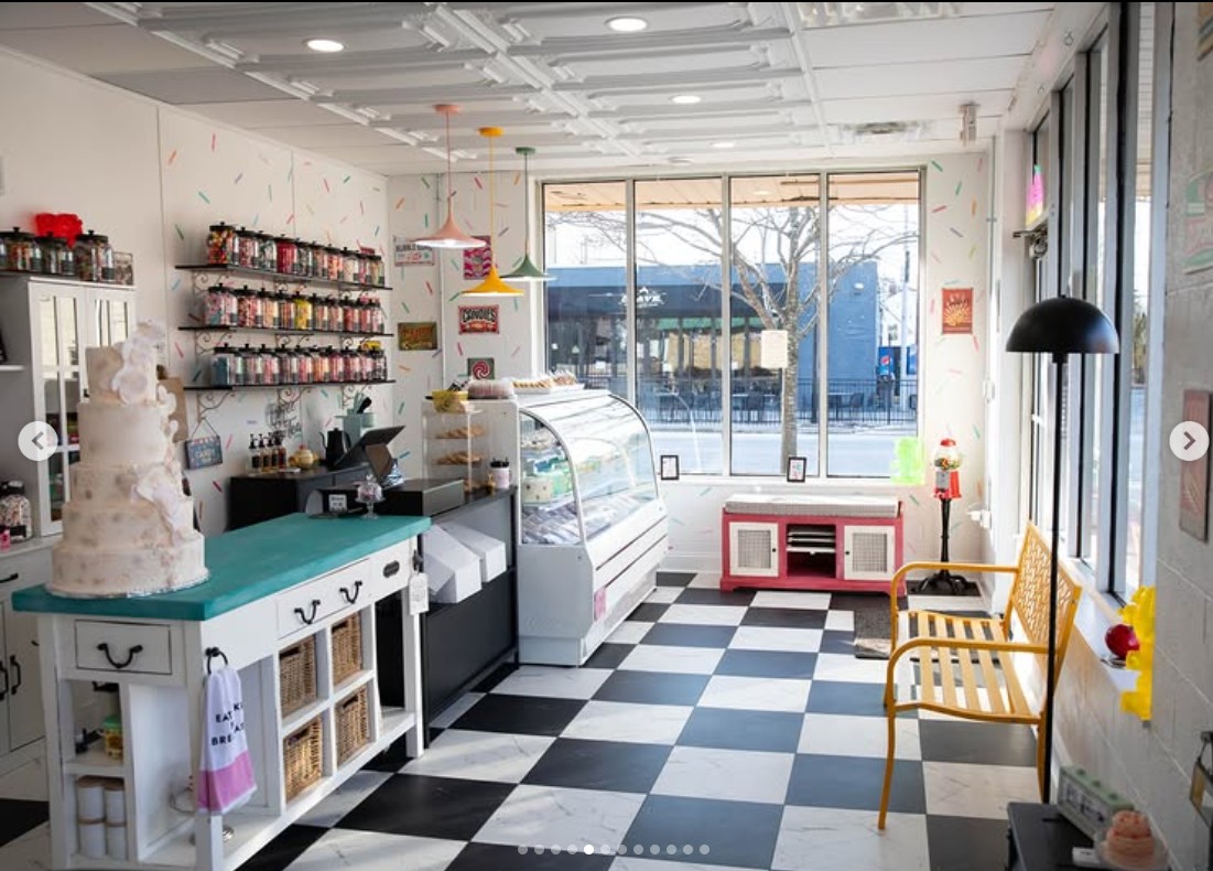 Interior of Gwendolyn Lee Cakery: checkerboard floor, teal counter with wedding cake, candy wall, yellow chair